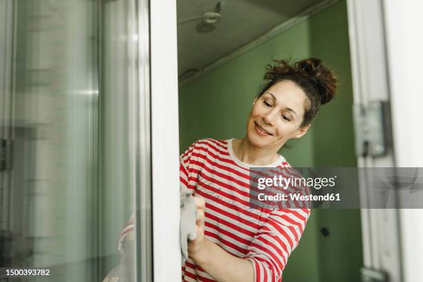 smiling woman cleaning window frame - woman cleaning for man stock-fotos und bilder