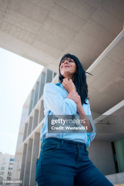 smiling businesswoman standing below office building - low angle view portrait stock pictures, royalty-free photos & images