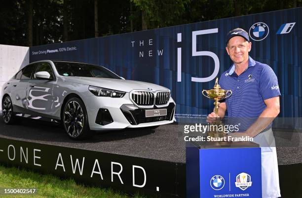 Ryder Cup Captain Luke Donald of England poses with the Ryder Cup trophy infront of a BMW i5 hole in one prize on the 17th hole during the pro-am...