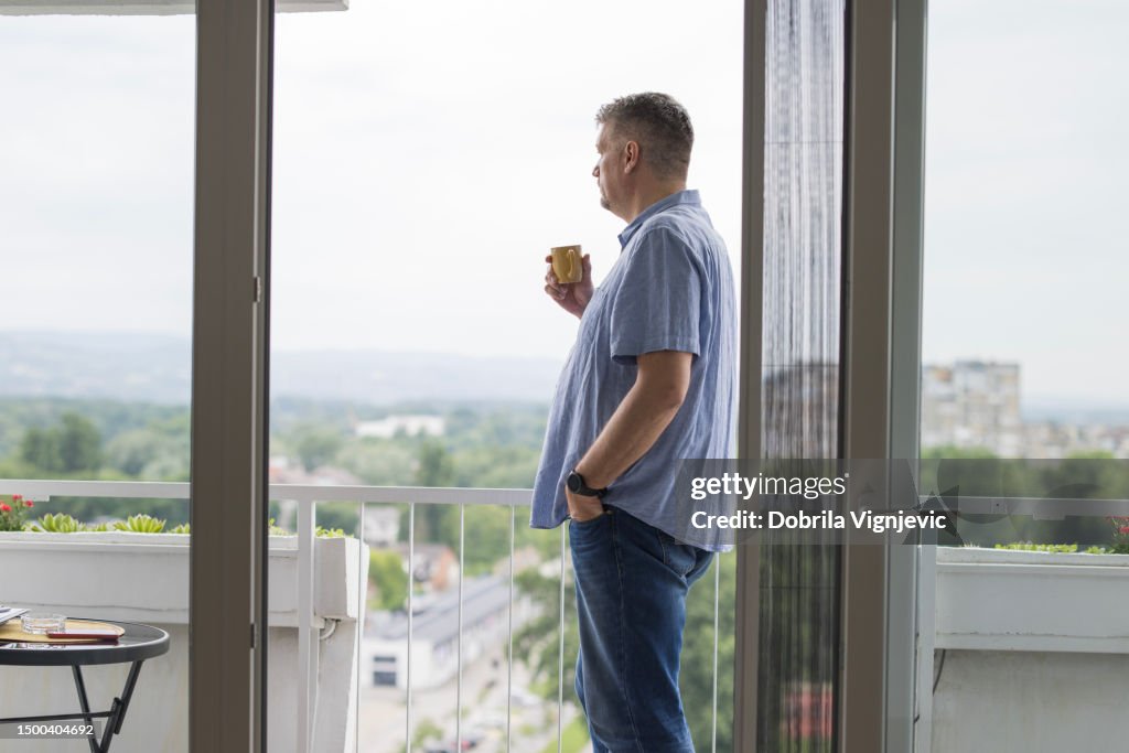 Hombre mirando por la ventana y bebiendo café