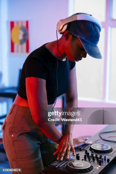 young dj operating and making music through sound mixer at home - electronic music production stock pictures, royalty-free photos & images