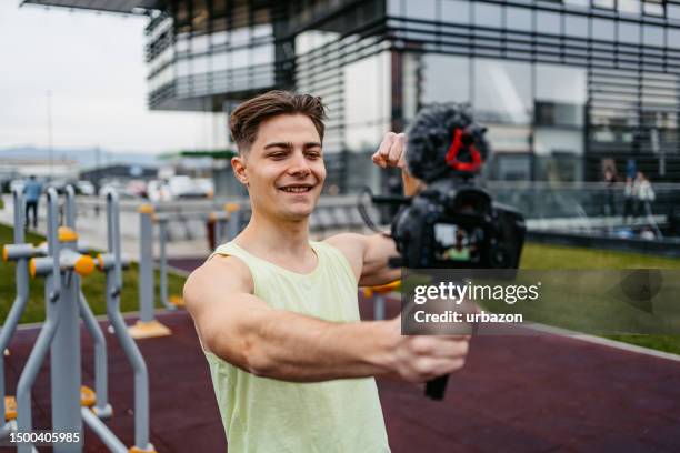 young muscular man recording vlog in an outdoor gym - alleen één man stockfoto's en -beelden