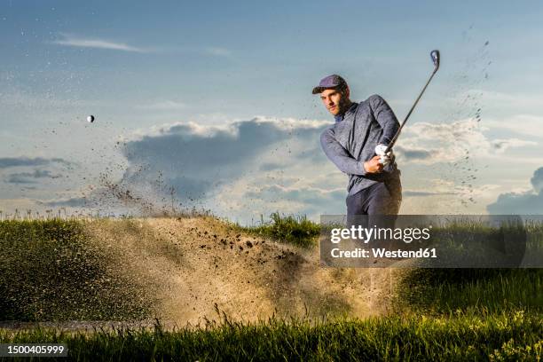 man playing golf standing on grass - golfschwung stock-fotos und bilder