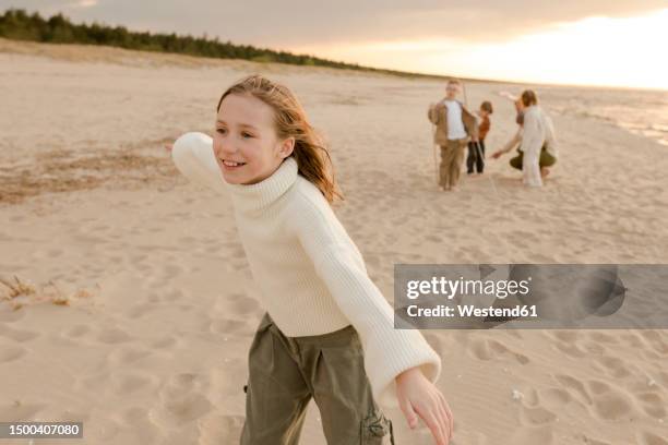 smiling girl playing at beach with family in background - pretending to be a plane stock pictures, royalty-free photos & images