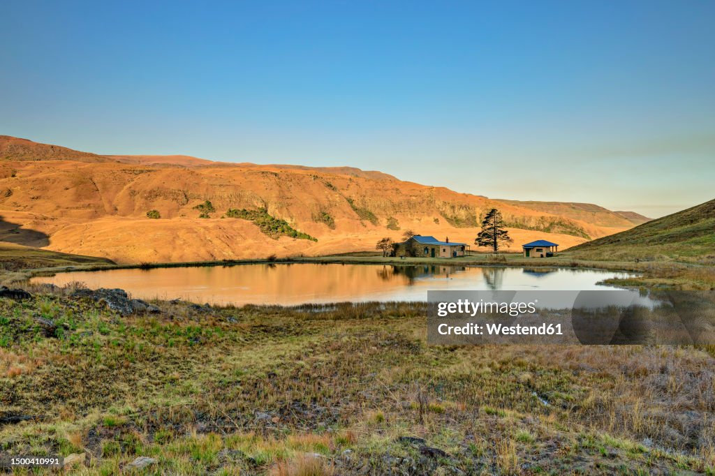 Cottages by lake in front of mountain at Lotheni, KwaZulu-Natal, Drakensberg, South Africa