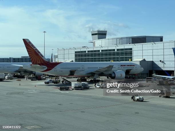 Large jetliner on airport tarmac with Air India logos visible, surrounded by clouds and clear sky, San Francisco International Airport, San...