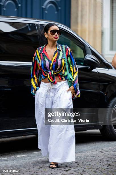 Guest wears white wide leg pants, cropped striped multi colored top outside Rhude during the Menswear Spring/Summer 2024 as part of Paris Fashion...
