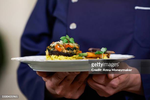 Chef Nina Curtis holds a plate of stuffed portobello mushrooms and creamy saffron-infused risotto, the main course for the state dinner for...