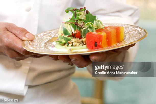 White House Executive Chef Cris Comerford holds a plate of marinated millet and grilled corn, kernel salad with compressed watermelon and avocado...