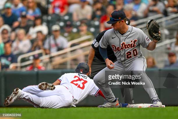 Royce Lewis of the Minnesota Twins dives back to first base ahead of the tag by Spencer Torkelson of the Detroit Tigers during the second inning...