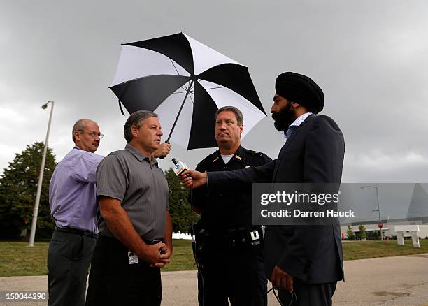 Oak Creek Mayor Steve Scaffidi and Police Chief John Edwards are interviewed across the street from where the mass shooting at the Sikh Temple of...
