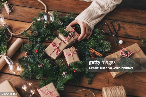 christmas wreath workshop. hands holding fir branches, pine cones, berries, thread, scissors on wooden table, flat lay. making rustic christmas wreath. authentic rural wreath - advent calendar stock pictures, royalty-free photos & images