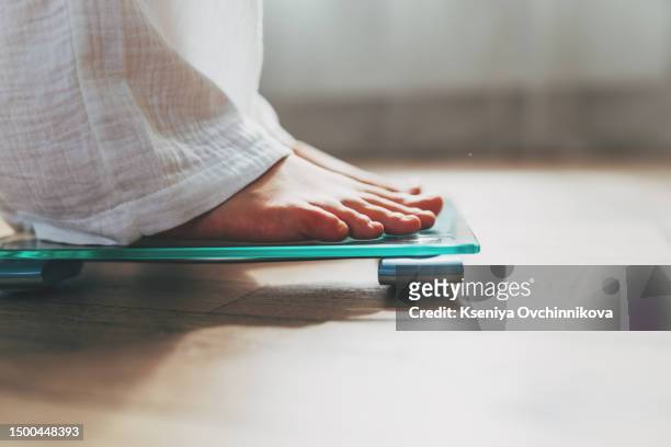 female feet standing on electronic scales for weight control on wooden background. the concept of slimming and weight loss - ダイエット ストックフォトと画像
