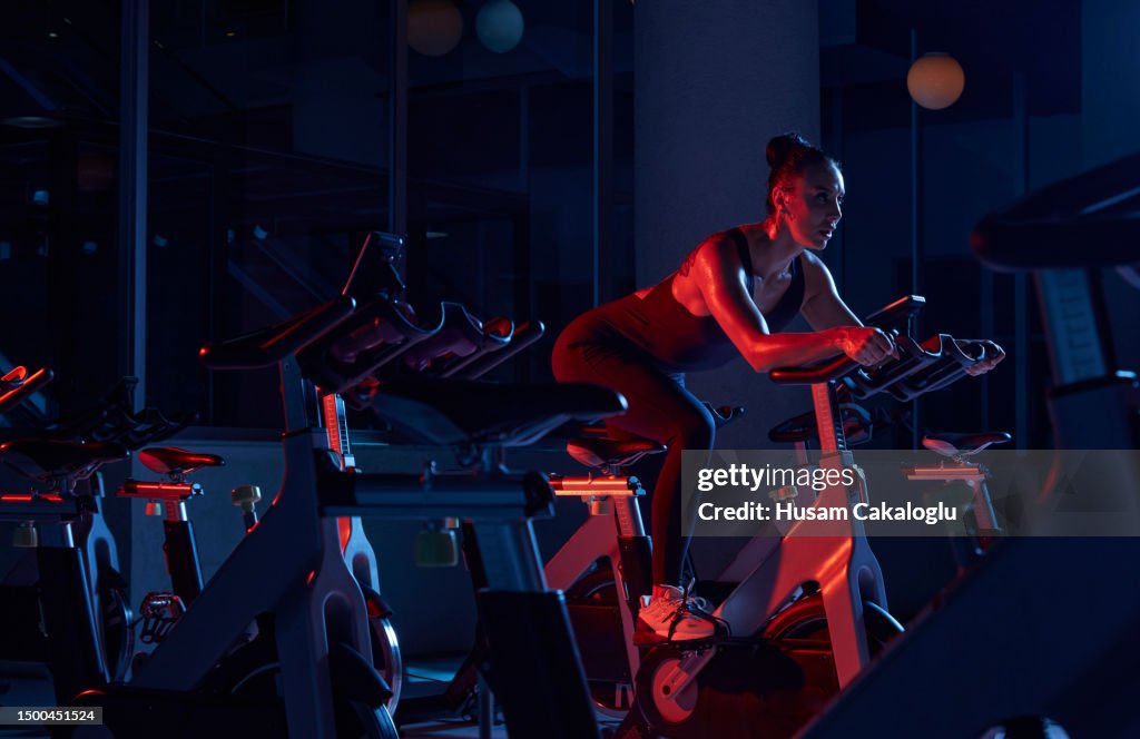 Sportlerin, die auf stationärem Fahrrad im Fitnessstudio trainiert.
