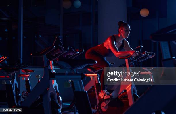 athlete woman training on stationary bike in fitness gym. - woman twirling stock pictures, royalty-free photos & images