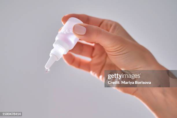 women's hands with a bottle of drops for the nose or eyes. - colírio imagens e fotografias de stock