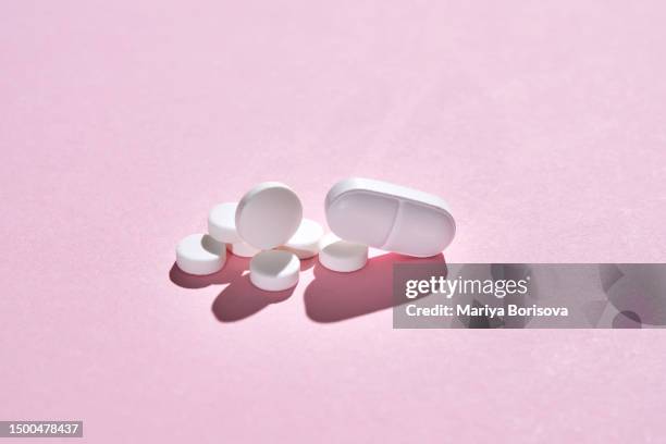 pills, vitamins and nutritional supplements on a pink background are stacked in bizarre figures. - streptomyces antibioticus imagens e fotografias de stock