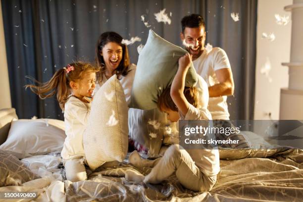 happy family having a pillow fight in the bedroom. - pillow fight stock pictures, royalty-free photos & images