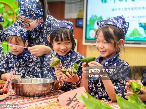 Students learn to wrap glutinous rice dumplings at a primary school to celebrate the upcoming Dragon Boat Festival on June 21, 2023 in Huzhou,...