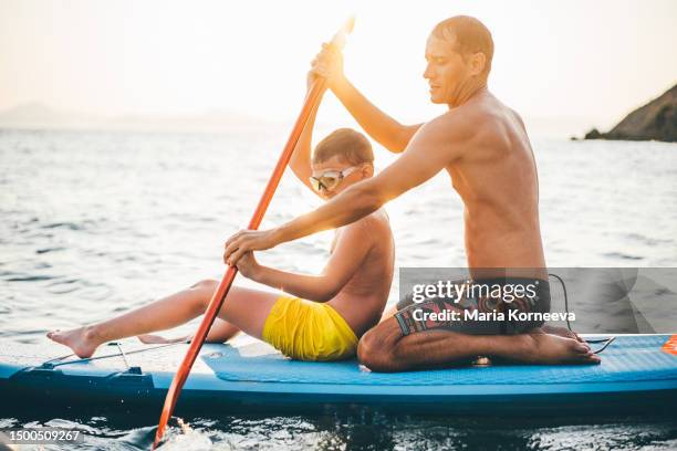 father and son having fun with paddle board. - paddle board men imagens e fotografias de stock