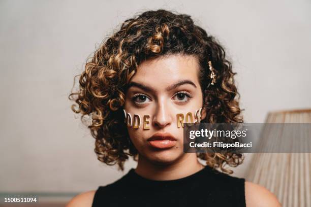 portrait of a young adult woman with the word "poderosa" made with stickers on her face - girl power stickers stock pictures, royalty-free photos & images