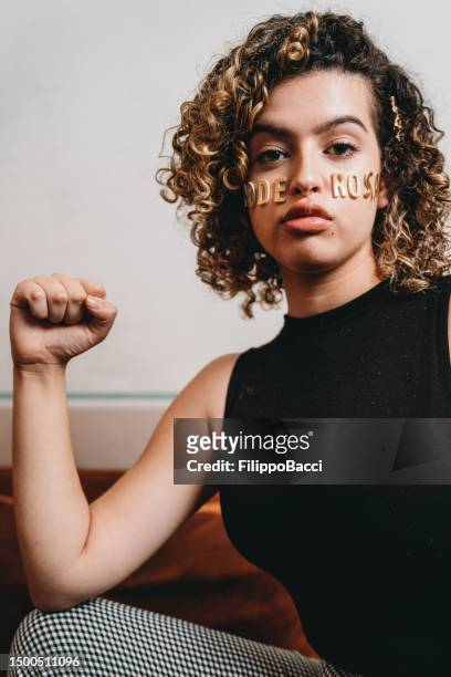 portrait of a young adult woman with the word "poderosa" made with stickers on her face - girl power stickers stock pictures, royalty-free photos & images