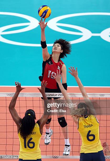 Saori Kimura of Japan spikes the ball as Fernanda Rodrigues and Thaisa Menezes of Brazil defend during the Women's Volleyball semifinal match on Day...