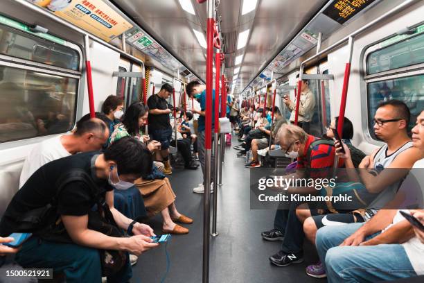 crowded asian people using mobile phone, ride subway train in hong kong city, inside view. commuter lifestyle, internet communication technology, asia public transportation concept - crowded train station smartphone stockfoto's en -beelden