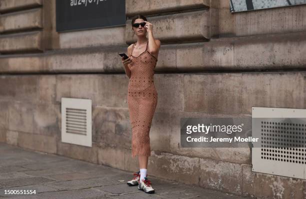 Fashion Week guest is seen wearing a transparent fringe beige dress, black shades and Adidas shiny silver sneaker with white socks outside Wales...