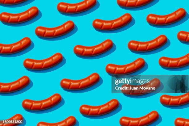 pattern of fake cooked sausages on a blue background - carne procesada fotografías e imágenes de stock