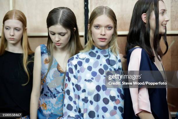 Backstage at the Edun show during New York Fashion Week Autumn/Winter 2016/17, one model wears a blue and gold printed shift dress, the other wears a...