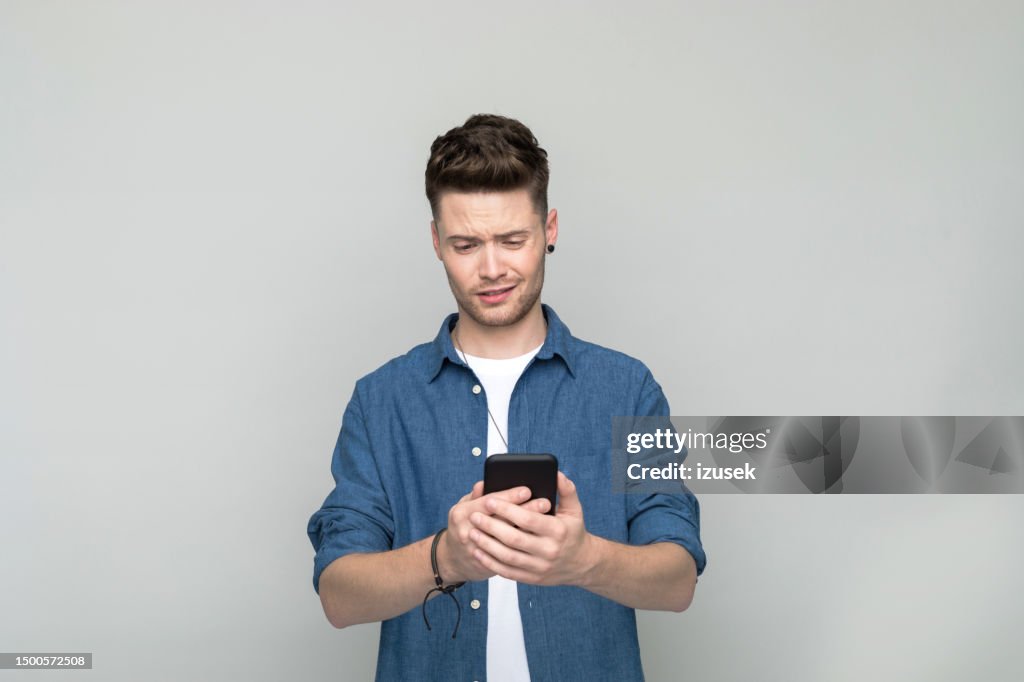 Confused young man using smart phone