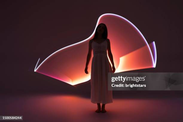 young woman in front of orange light trails. - long exposure dance stock pictures, royalty-free photos & images