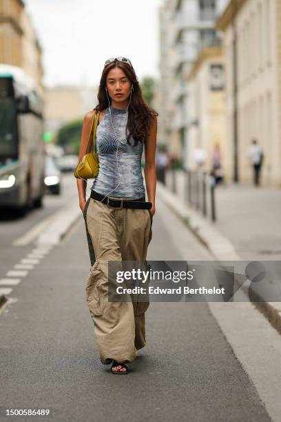 Guest wears white sunglasses, gold earrings, a pale blue and black zebra print pattern turtleneck / halter-neck / sleeveless tank-top, a yellow gold...