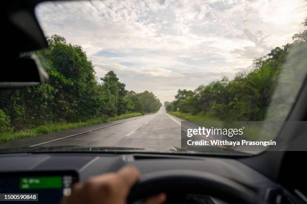 hands of car driver on steering wheel, road trip, driving on highway road - perspectiva de un coche fotografías e imágenes de stock