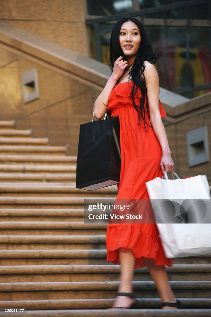 Woman carring shopping bags walking along street