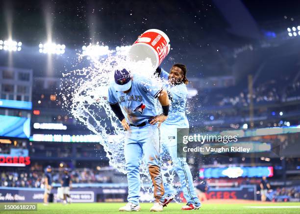 Daulton Varsho of the Toronto Blue Jays is doused with water by Vladimir Guerrero Jr. #27 following a win against the Houston Astros at Rogers Centre...