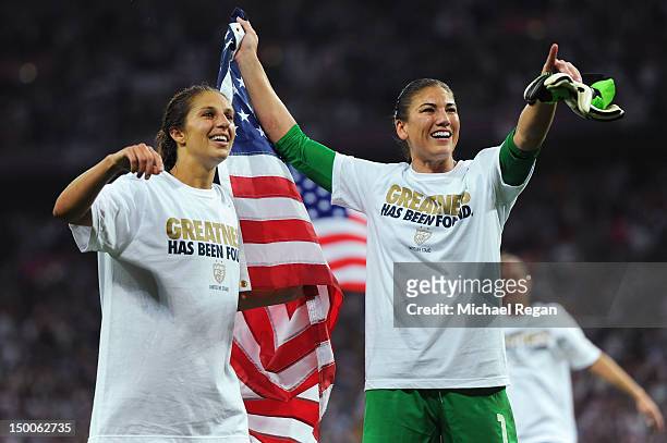 Hope Solo and Carli Lloyd of the United States celebrate with the American flag after defeating Japan by a score of 2-1 to win the Women's Football...