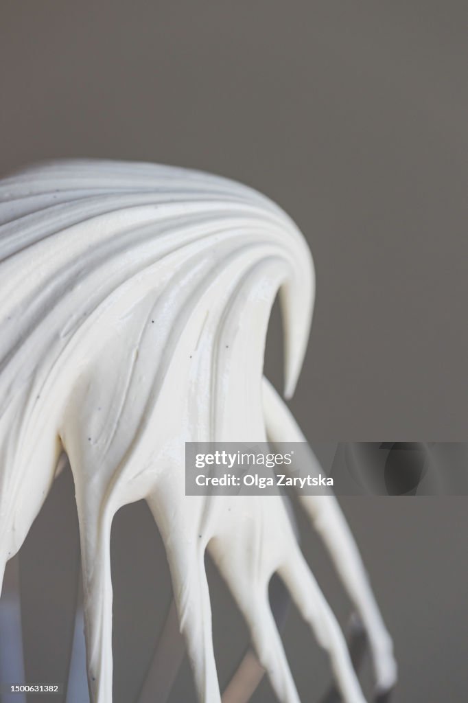 Close-up of whipped ganache or cream with vanilla seeds on whisk.
