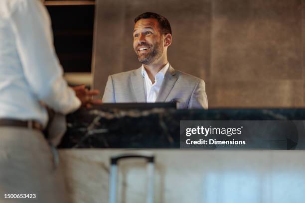 happy hotel receptionist having conversation with client - hotel reception stockfoto's en -beelden