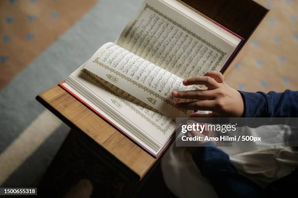 midsection of woman reading,indonesia - coran photos et images de collection