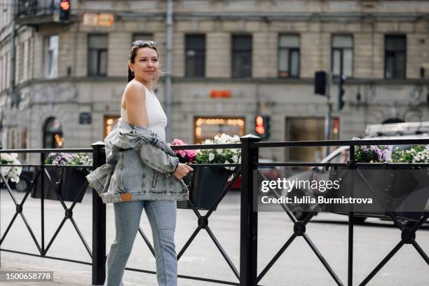 good-looking lady walking along city street on summer evening - off the shoulder coat stock pictures, royalty-free photos & images