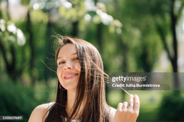 alluring lady with long brown hair looking at camera with joyful look - ranke stock-fotos und bilder