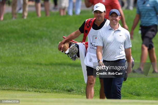 Rory McIlroy of Northern Ireland smiles as he approaches the green with caddie Harry Diamond after making a hole-in-one on the eighth hole during the...