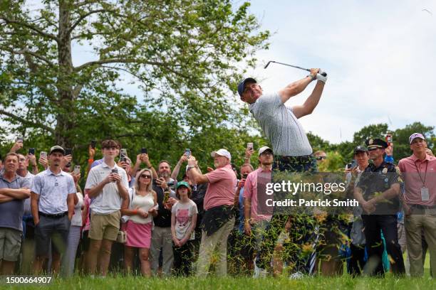 Rory McIlroy of Northern Ireland plays his second shot on the fourth hole as fans look on during the first round of the Travelers Championship at TPC...