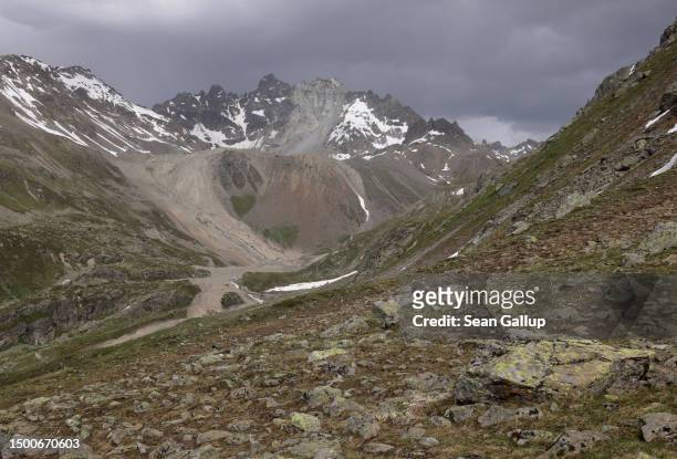 The partially collapsed Fluchthorn mountain stands above a swath of rock and gravel deposited by its rockslide into the valley below on June 22, 2023...