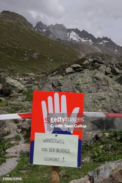 Sign warns that local authorities have closed the hiking trail as partially collapsed Fluchthorn mountain stands in the distance on June 22, 2023...