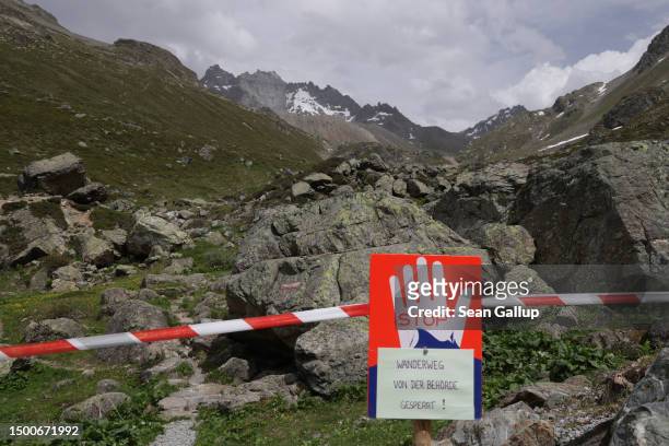 Sign warns that local authorities have closed the hiking trail as partially collapsed Fluchthorn mountain stands in the distance on June 22, 2023...