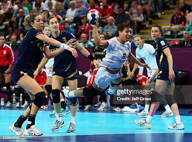 Ana Dokic of Montenegro shoots past Begona Fernandez Molinos and Andrea Barno San Martin of Spain during the Women's Handball semifinal game between...