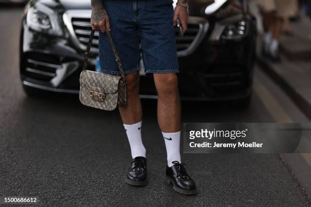 Fashion Week guest is seen wearing black shades, denim vest and matching jeans shorts, Gucci x Balenciaga Horsebit logo beige bag, Nike white socks...